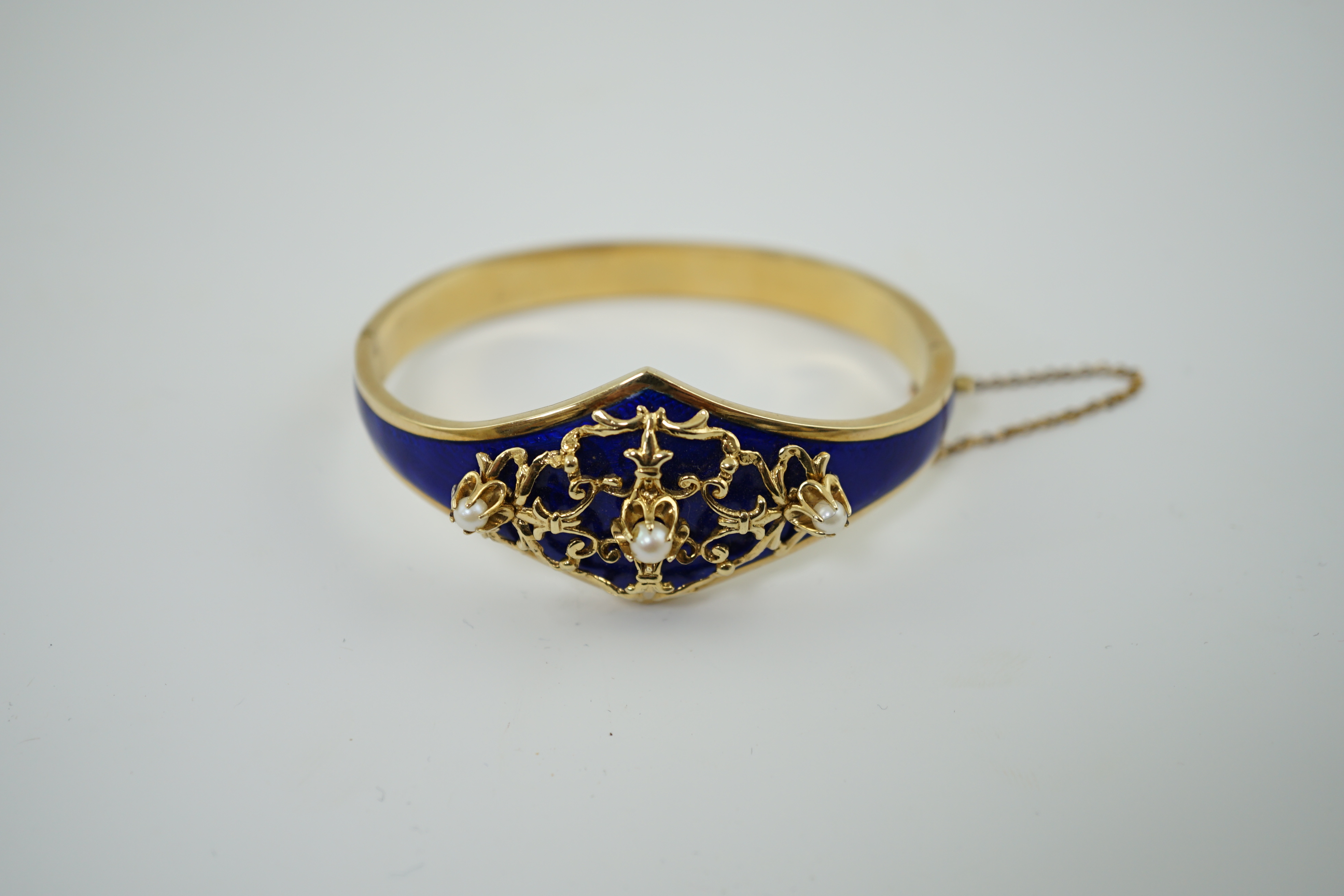 A continental Victorian style 14k gold, blue guilloche enamel and three stone cultured pearl set hinged bangle